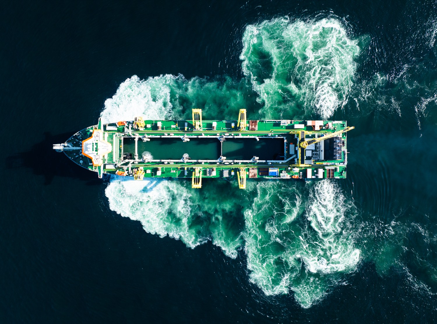 Top-down aerial of the Seaway underway during trials, her open hopper running most of her length and propeller wash churning the sea behind her